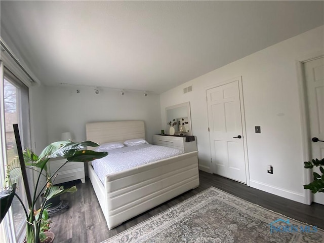 bedroom with baseboards, visible vents, and wood finished floors