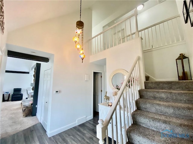 staircase with baseboards, high vaulted ceiling, and wood finished floors