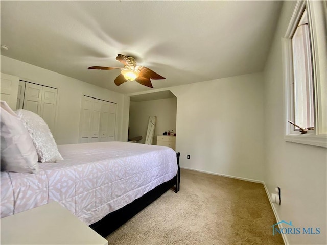bedroom with carpet floors, baseboards, multiple closets, and ceiling fan