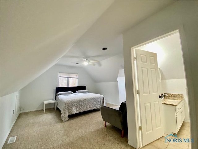 bedroom featuring vaulted ceiling, a sink, light colored carpet, visible vents, and ceiling fan