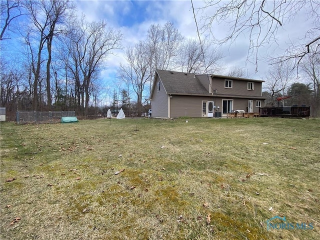 rear view of house featuring fence, a yard, and a wooden deck