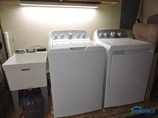 clothes washing area featuring washing machine and dryer, a sink, and laundry area