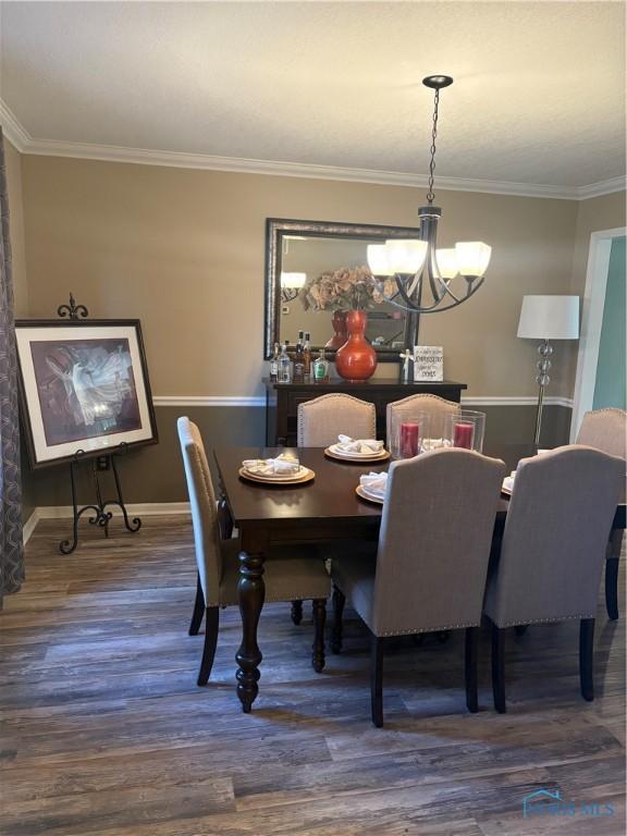 dining area featuring baseboards, crown molding, wood finished floors, and an inviting chandelier