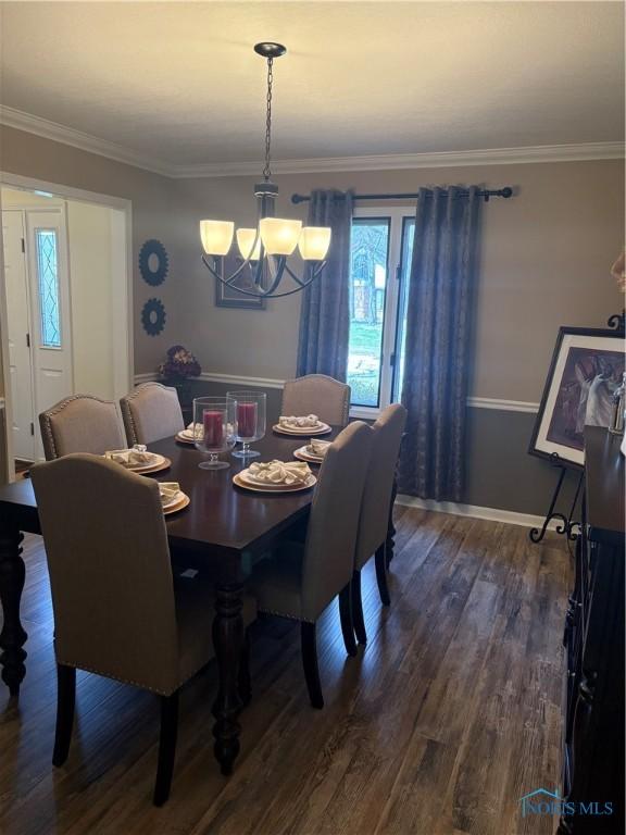 dining space with baseboards, ornamental molding, a chandelier, and dark wood finished floors