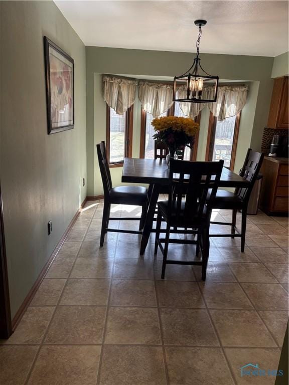 dining area featuring baseboards, a healthy amount of sunlight, and an inviting chandelier
