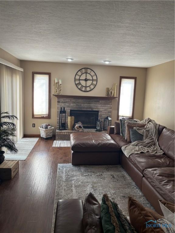 living area with baseboards, a fireplace, wood finished floors, and a textured ceiling