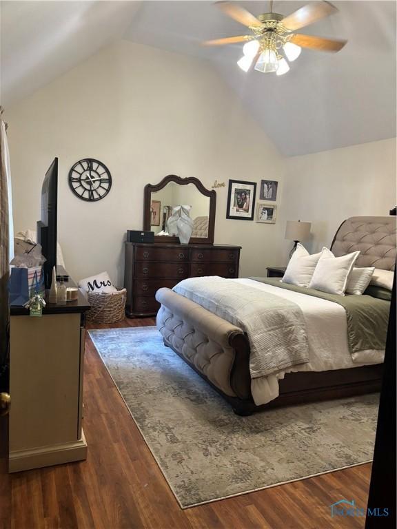 bedroom with dark wood-style flooring, vaulted ceiling, and ceiling fan