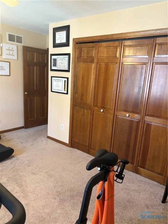 exercise room with light carpet, baseboards, and visible vents