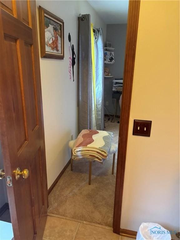 corridor with baseboards, light tile patterned floors, and light colored carpet