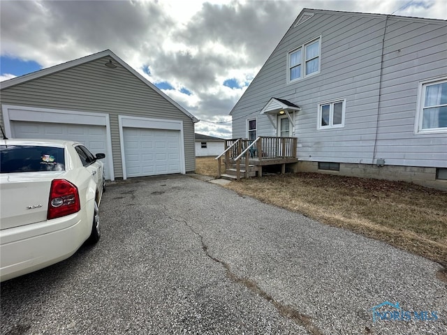 view of property exterior with an outbuilding, a garage, and aphalt driveway