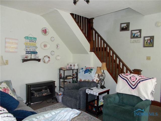 carpeted living area with a wood stove and stairs
