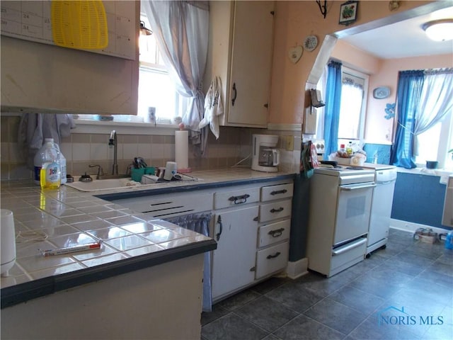 kitchen featuring white cabinets, tile counters, white range with gas cooktop, and plenty of natural light
