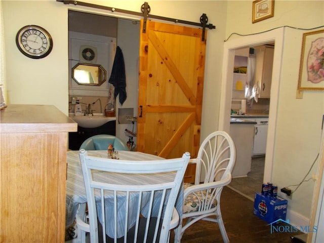 dining space with wood finished floors and a barn door