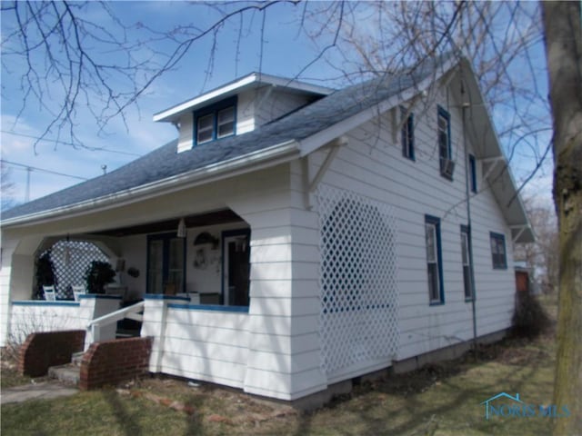view of side of property with a shingled roof and covered porch