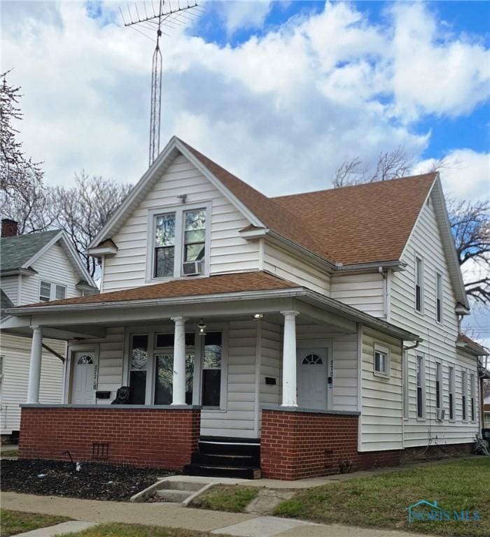 view of front of property featuring brick siding, a porch, crawl space, and roof with shingles