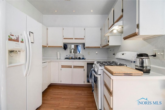 kitchen with light countertops, a sink, light wood-type flooring, under cabinet range hood, and white appliances