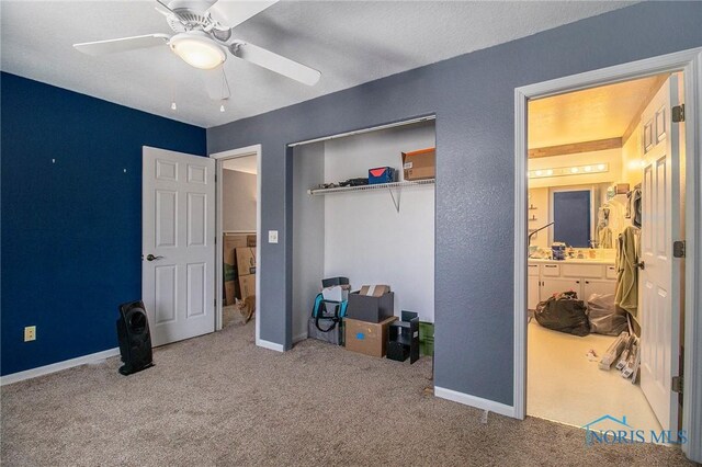 carpeted bedroom featuring a closet, ensuite bathroom, baseboards, and a ceiling fan