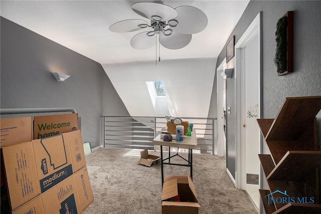 office area with baseboards, carpet floors, vaulted ceiling with skylight, and a ceiling fan