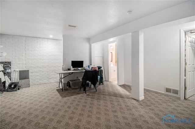 office space with visible vents, carpet, and brick wall