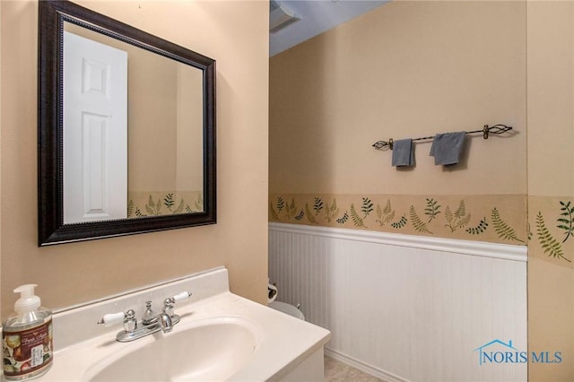 bathroom with a wainscoted wall and vanity