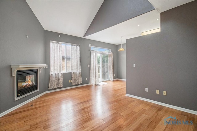 4014 Stonehenge Dr Unit 4014, Sylvania, OH 43560 - unfurnished living room with a glass covered fireplace, wood finished floors, vaulted ceiling, and baseboards