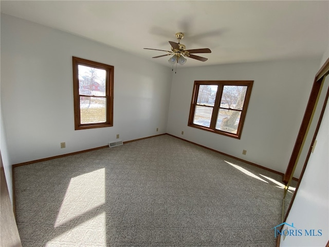 unfurnished bedroom with carpet flooring, a ceiling fan, baseboards, and visible vents