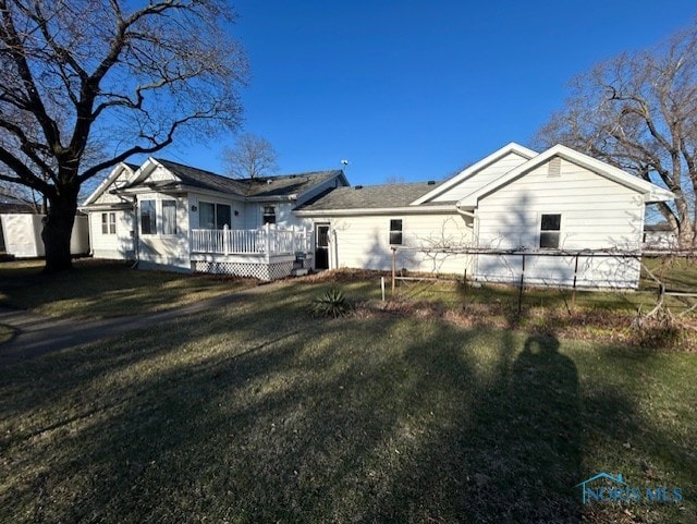 rear view of house featuring a lawn, a wooden deck, and fence
