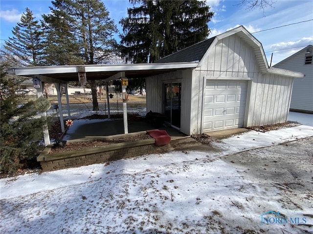 snow covered garage with an attached carport