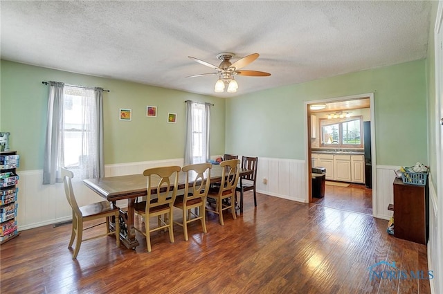 406 N Main St, Continental, OH 45831 - dining space with dark wood-style flooring, a textured ceiling, a ceiling fan, and wainscoting