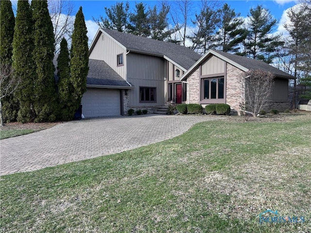 view of front of property featuring driveway, an attached garage, roof with shingles, and a front yard