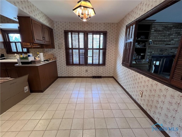 kitchen with a chandelier, visible vents, light tile patterned floors, baseboards, and wallpapered walls