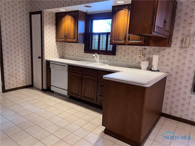 kitchen with light countertops, a sink, white dishwasher, baseboards, and wallpapered walls