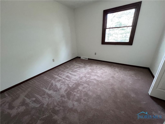 carpeted empty room featuring baseboards and visible vents