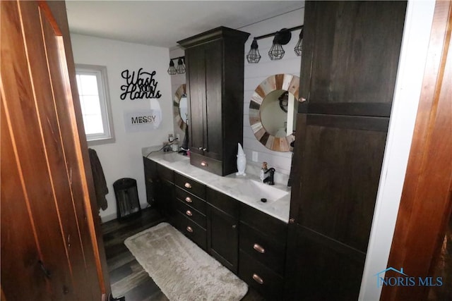 bathroom featuring double vanity, a sink, and wood finished floors
