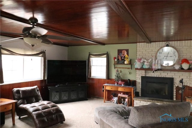 carpeted living room with wooden ceiling, ceiling fan, wooden walls, and a brick fireplace