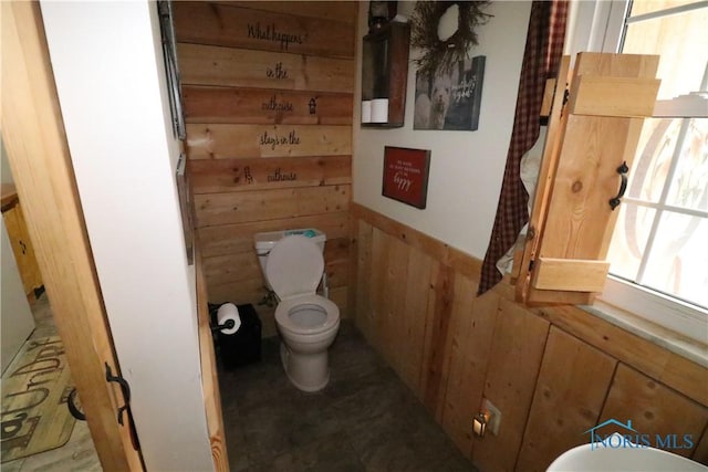 bathroom featuring toilet and wooden walls