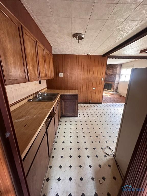 41 Dickens Dr, Toledo, OH 43607 - kitchen with wood walls, a sink, brown cabinetry, a fireplace, and light floors
