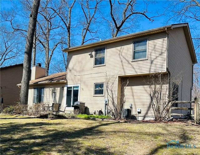 rear view of property featuring a lawn and a chimney