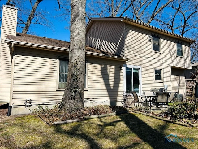 rear view of property featuring a yard, a patio area, and a chimney