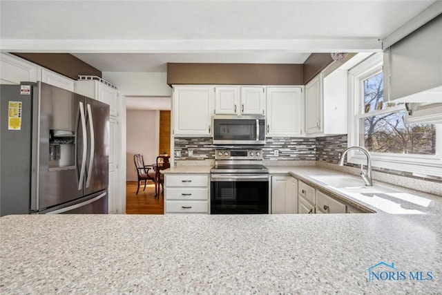 kitchen with white cabinetry, light countertops, backsplash, and stainless steel appliances