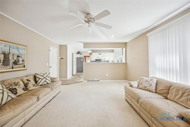 living room with visible vents, baseboards, ceiling fan, ornamental molding, and carpet floors