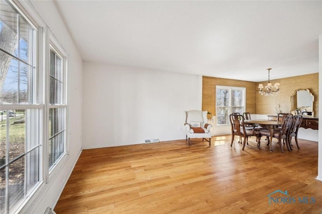 dining space with visible vents, a chandelier, and light wood finished floors