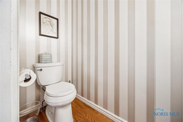 bathroom with toilet, wallpapered walls, and wood finished floors