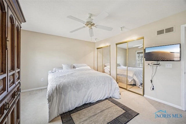 bedroom with light carpet, baseboards, multiple closets, and visible vents