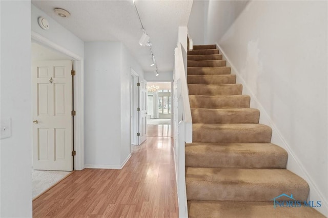 stairs with rail lighting, baseboards, and wood finished floors