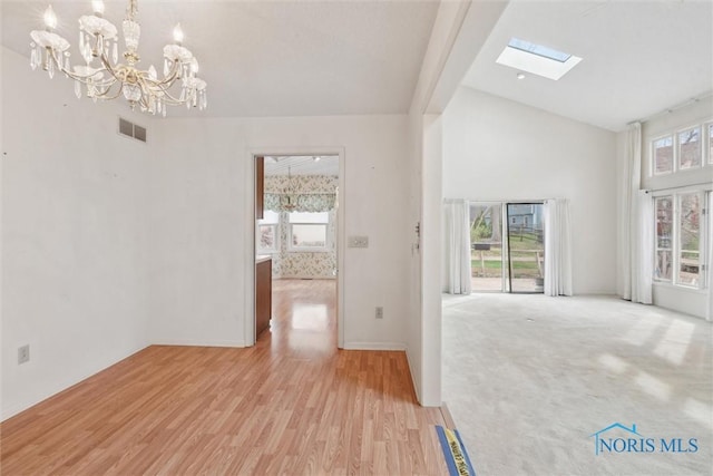 interior space with visible vents, light wood-style floors, a healthy amount of sunlight, and an inviting chandelier