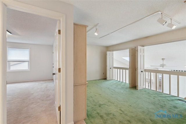 hall featuring track lighting, a textured ceiling, and carpet
