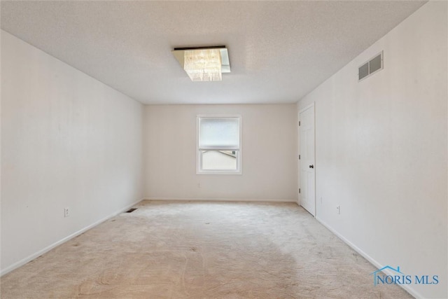 carpeted empty room with baseboards, visible vents, and a textured ceiling