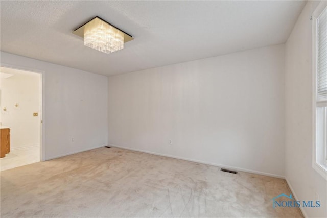 unfurnished room with carpet floors, visible vents, and baseboards