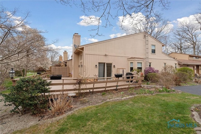 back of house with a yard, a chimney, and fence